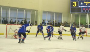 アイスホッケー少年１回戦で岡山のゴールを攻める滋賀（青）＝２日、ヘルスピア倉敷