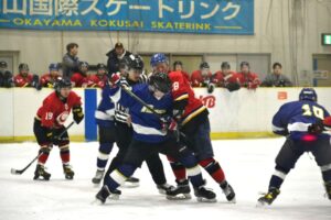 アイスホッケーのゲームでもみ合う選手の間に割って入り仲裁するレフリー＝１日、岡山国際スケートリンク