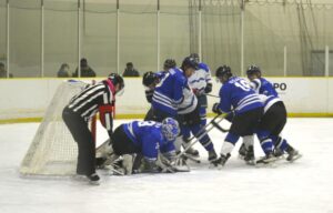 アイスホッケー成年準決勝で激しい攻防を繰り広げる神奈川と大阪（青）＝４日、岡山国際スケートリンク