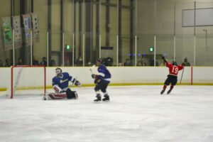 アイスホッケー成年１回戦でゴールを決め喜ぶ沖縄県チーム（赤）＝１日、岡山国際スケートリンク