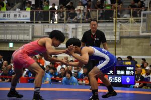 レスリング少年男子フリースタイル51キロ級１回戦で京都の池田響介と組み合う滋賀の柴田寛大（左）＝29日、栗東市民体育館